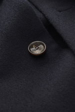 Nahaufnahme der Montecore Cashmere Jacke navy aus reinem Cashmere, Fokus auf Knopf mit Logo und weichem, ungefüttertem Stoff.