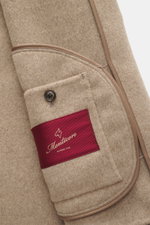 Nahaufnahme der Montecore Cashmere Jacke beige meliert von innen mit rotem Label, Umlegekragen und feinen Nähten, weicher Griff sichtbar.