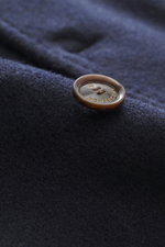 Close-up from a side angle of the Montecore Cashmere Jacket navy showing a brown button with "MONTECORE" engraved on soft navy pure cashmere fabric.