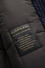 Nahaufnahme des Labels des Sealup Parka 'Hurricane' navy, fotografiert aus seitlicher Perspektive, zeigt hochwertige Microfaser, wind- und wasserabweisend, Regular Fit, Kapuze, zwei-Wege-Reißverschluss, paspelierte Taschen, Knopfärmelabschlüsse, regulierb