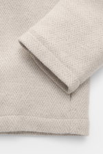 Close-up front-side view of the Colombo Jacket beige melange, a slim fit with a soft touch mix of kid cashmere and kid wool, featuring a two-way zipper, hood with drawstring, side seam pockets, smooth lining, and two inside pockets.