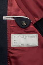 Nahaufnahme der Innenseite der Brunello Cucinelli Cashmere Jacke navy mit rotem Futter, Knopf und Label, Detail der hochwertigen Verarbeitung.