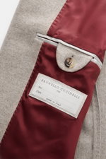 Detailaufnahme der Innenseite der Brunello Cucinelli Cashmere Jacke beige meliert, halb gefüttert mit rotem Futter, Knopf und Label.