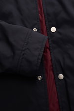 Brunello Cucinelli Jacke navy im Detail von oben fotografiert, weiche Microfaser, leichte Wattierung, Druckknopfleiste, rotes Futter sichtbar.