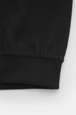 The Row Cashmere Blouson 'Olek' schwarz, Detailansicht des elastischen Saumbündchens aus weichem, voluminösem Kaschmirfilz, aufgenommen aus frontaler Nahperspektive.