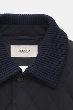 Nahaufnahme der Agnona Steppjacke navy von oben, zeigt Umlegekragen mit Rippstrickbesatz, hochwertige Microfaser, glatter Griff, Regular Fit, Vier-Knopf-Stil, Fronttaschen mit Druckknopf, klassische Brusttasche, rückwärtige Seitenschlitze, geschmeidiger F