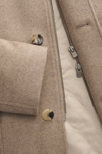 Nahaufnahme von Reißverschluss, Knopf und Ärmel der Agnona Cashmere Jacke beige meliert, Slim Fit, reiner Cashmere mit Wattierung, glattem Innenfutter, variablen Revers und aufgesetzter Tasche, fotografiert aus frontaler Perspektive.