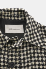 Nahaufnahme der Ami Paris Wolljacke schwarz/creme kariert von oben auf den Umlegekragen mit Hahnentritt-Muster, Knöpfen und griffiger Qualität.