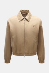 Frontansicht des Ami Paris Blouson beige aus Baumwoll-Twill, Unisex Regular Fit mit weichem Griff, Zwei-Wege-Reißverschluss, Umlegekragen, tonalem Logo-Stitching, schrägen Fronttaschen mit Druckknopf, elastischen Saumabschlüssen, softem Twill-Futter und z