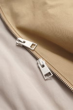 Nahaufnahme des robusten Zwei-Wege-Reißverschlusses eines Ami Paris Blouson beige aus Baumwoll-Twill mit softem Twill-Futter, Regular Fit, Unisex-Modell.