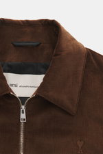 Nahaufnahme des Ami Paris Cord-Blouson braun von vorne, Cord aus Baumwolle, weicher Griff, Regular Fit, Unisex-Modell, robuster Zwei-Wege-Reißverschluss, Umlegekragen, schräge Fronttaschen mit Druckknopf, tonales Logo-Stitching auf der Brust, elastische S