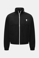 Schwarzer Ami Paris Blouson 'Windbreaker' im Regular Fit, frontal fotografiert, mit hochwertiger Microfaser, glattem Griff, robustem Reißverschluss, versteckter Kapuze, paspelierten Fronttaschen mit Knopf, Logo-Detail, elastischen Bündchen und geschmeidig