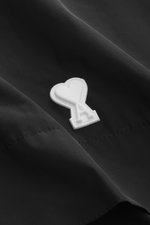 Nahaufnahme des weißen Logo-Details auf der Brust des Ami Paris Blouson 'Windbreaker' schwarz, hochwertige Microfaser, glatter Griff.