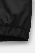 Ami Paris Blouson 'Windbreaker' schwarz, Detailaufnahme elastischer Saum und Ärmelbündchen, hochwertige Microfaser, glatter Griff, Regular Fit, robuster Reißverschluss, versteckte Kapuze, paspelierte Fronttaschen mit Knopf, Logo-Detail, geschmeidiger Futt