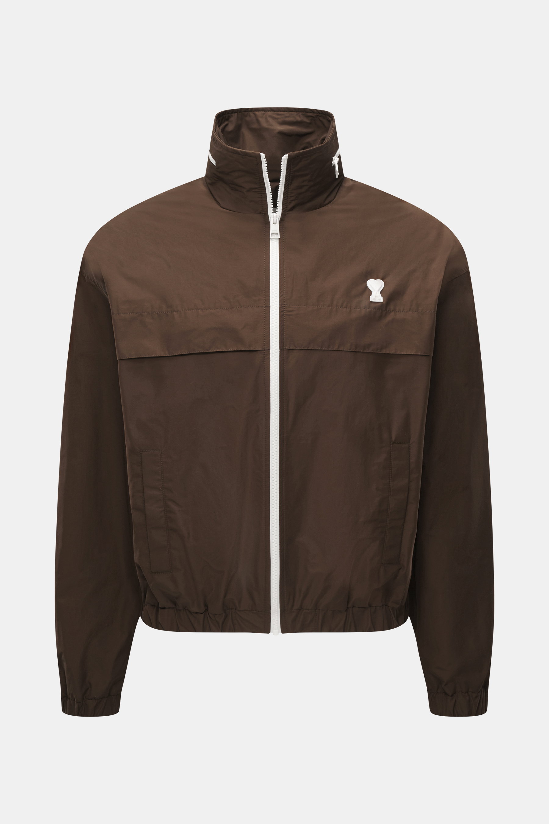 Vorderansicht des Ami Paris Blouson 'Windbreaker' braun aus hochwertiger Microfaser mit glattem Griff, Regular Fit, robustem Reißverschluss, im Kragen versteckter Kapuze, paspelierten Fronttaschen mit Knopf, Logo-Detail auf der Brust, elastischen Saum- un