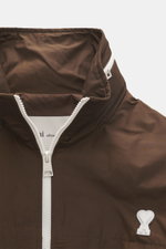 Nahaufnahme des Kragens des Ami Paris Blouson 'Windbreaker' braun mit hochwertiger Microfaser, glattem Griff, robustem Reißverschluss, Logo-Detail, Regular Fit, elastischen Bündchen, versteckter Kapuze, paspelierten Fronttaschen und geschmeidigem Futterst