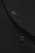 Close-up front view of Jacquemus Blouson black showing pure new wool fabric, soft touch, oversized fit, turn-down collar, smooth button placket, piped front pockets, and elastic hem and sleeve cuffs.