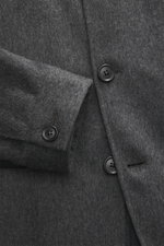 Nahaufnahme der Zegna Cashmere Jacke grau meliert, fotografiert von schräger Obenperspektive, zeigt weichen Griff, Vier-Knopf-Leiste, Stehkragen mit Knopfriegel und Ärmel mit Knopf.