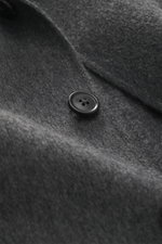 Nahaufnahme eines schwarzen Knopfs auf der grau melierten Oberfläche der Zegna Cashmere Jacke grau meliert aus reiner Wolle, weicher Griff.