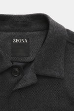 Nahaufnahme aus schräger Perspektive der Zegna Cashmere Jacke dunkelgrau/schwarz kariert mit Umlegekragen, Slim Fit, vier Knöpfen, reiner Cashmere, weichem Griff, halb gefüttert, Manschettenärmel, aufgesetzten Fronttaschen, rückwärtigen Seitenschlitzen un
