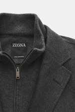 Nahaufnahme des Zegna Cashmere Sakko dunkelgrau meliert von oben, zeigt Revers, Zip, feines Kaschmir, weichen Griff und Innenlabel.