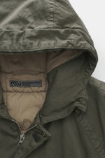 Nahaufnahme der Kapuze der Massimo Osti Studio Jacke oliv, Mix aus Baumwolle und Microfaser, weicher Griff, Regular Fit, Zwei-Wege-Reißverschluss, Windblende mit Druckknöpfen, Kapuze mit Tunnelzug, Handwärmetaschen, Fronttaschen mit Patte, kleines Metall-