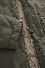 Nahaufnahme der geöffneten Massimo Osti Studio Jacke oliv mit Baumwoll-Microfaser-Mix, Regular Fit, Zwei-Wege-Reißverschluss, weichem Griff, Kapuze mit Tunnelzug, Windblende mit Druckknöpfen, Handwärmetaschen, Fronttaschen mit Patte, kleinem Metall-Logo, 