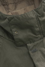 Nahaufnahme der Massimo Osti Studio Jacke oliv von innen mit gestepptem Futterstoff, Innentasche und kleinem Metall-Logo, Mix aus Baumwolle und Microfaser, weicher Griff, Regular Fit, Zwei-Wege-Reißverschluss, Windblende mit Druckknöpfen, Kapuze mit Tunne