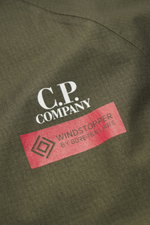 Nahaufnahme der olivgrünen C.P. Company Daunenjacke mit Ripstop-Microfaser, glattem Griff, windabweisend, wasserdicht, Regular Fit.