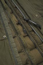 Nahaufnahme aus schräger Perspektive der Reißverschlüsse und des Materials der C.P. Company Daunenjacke oliv mit Ripstop, windabweisend, wasserdicht, Regular Fit, Kapuze mit Goggles, elastischen Ärmelabschlüssen, verstellbarem Saum, zwei Innentaschen und 