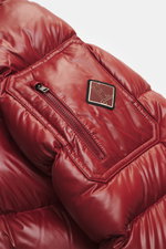 Nahaufnahme der roten Herno Daunenjacke rot von schräg oben, zeigt hochwertige Microfaser mit glattem Griff, wärmende Daunenfüllung, Zipper-Tasche mit Patch am Ärmel.