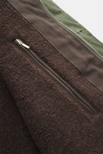 Nahaufnahme der Innenseite der Manifattura Ceccarelli Wachsjacke "Weekender" oliv aus weichem Teddyfutter, wasserabweisender gewachster Baumwolle, materialtypischer Haptik, Slim Fit, leichter Wollwattierung, Zwei-Wege-Reißverschluss, Windblende mit Knöpfe