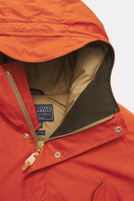 Close-up front view of the Manifattura Ceccarelli Down jacket 'Fisherman' orange showcasing pure cotton fabric, soft touch, regular fit, warm down filling, two-way zipper, wind flap with press studs, high-closing collar with hood, raglan sleeves, slanted 