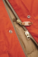Close-up front view of the Manifattura Ceccarelli Down jacket 'Fisherman' orange showing pure cotton fabric, soft touch, regular fit, warm down filling, two-way zipper, wind flap with press studs, high-closing collar with hood, raglan sleeves, slanted fro