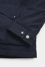 Close-up front-side view of Manifattura Ceccarelli Down jacket 'Fisherman' navy showing sleeve cuff with press stud tabs, slanted front pocket with flap, pure cotton, soft touch, regular fit, warm down filling, two-way zipper, wind flap with press studs, 
