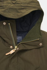 Close-up front view of Manifattura Ceccarelli Down jacket 'Fisherman' olive, showing high-closing collar with hood, two-way zipper, wind flap with press studs. Made of pure cotton with soft touch, regular fit, warm down filling, raglan sleeves, slanted fr