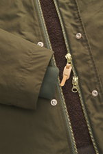Nahaufnahme der Manifattura Ceccarelli Jacke 'Shelter' dark olive von oben, Slim Fit aus reiner Baumwolle mit robustem Zwei-Wege-Reißverschluss, Windblende mit Druckknöpfen, hochschließendem Stehkragen, regulierbarer Kapuze mit Schirm, paspelierten Frontt