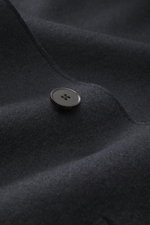 Close-up front view of Harris Wharf London Wool jacket dark navy showing a single dark button on knitted and felted virgin wool fabric, highlighting heavy, sturdy quality with raw-edge finish, slim fit, four-button placket, turn-down collar, patch pockets