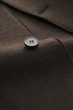 Close-up, top-down view of Harris Wharf London Wool jacket dark brown showing a single button on knitted and felted virgin wool with heavy, sturdy quality, raw-edge finish, slim fit, four-button placket, turn-down collar, patch pockets, and unconstructed 