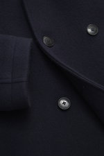 Nahaufnahme der Closed Cabanjacke navy, fotografiert aus schräger Perspektive, zeigt Slim Fit, weichen Griff, Mix aus Wolle und Microfaser, zweireihige Vier-Knopf-Leiste, variablen Kragen, schräge Hüfttaschen, gestepptes Innenfutter und eine Innentasche.