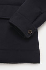 Nahaufnahme der Ärmelmanschette und Hüfttasche der Moorer Cashmere Cabanjacke 'Bas' dunkelbraun, Slim Fit, mit Knopfverschluss, gestepptem Futter, Daunenfüllung und variablen Kragen. Fotografiert aus seitlich-abgewinkelter Perspektive.