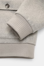 Nahaufnahme des Ärmelbündchens und Knopfes vom Gimo's Blouson grau meliert, aus Schurwollmix mit Rippbündchen, Slim Fit und Lammfellbesatz.