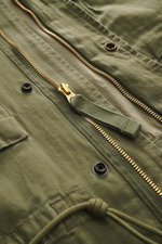 Nahaufnahme der Polo Ralph Lauren Jacke 'Iconic Field Jacket' oliv mit Fokus auf zwei-Wege-Reißverschluss, Druckknöpfen und Brusttaschen, Slim Fit, reine Baumwolle.