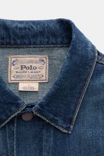Nahaufnahme aus schräger Perspektive der Polo Ralph Lauren Jeansjacke rauchblau aus Denim reiner Baumwolle mit Slim Fit, Kontrastnähten, Umlegekragen, Six-Knopf-Leiste, Brusttaschen mit Patte, paspelierten Eingriffstaschen, Ärmelabschlüssen mit Knopf und 