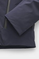 Close-up front-side view of dark blue UBR Down jacket 'Phantom' showcasing elastic microfiber, water-repellent fabric, light down filling, slim fit, two-way zipper, high stand-up collar, practical hood, reflective UBR logo on chest, zipper front pockets, 