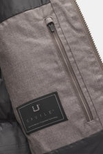 Close-up, top-down view of the UBR Merino Down Jacket 'Savile' grey-brown melange showing the zipper pocket, label, and fabric texture. With the down jacket 'Savile' by UBR, we are well prepared for the next cold season, as this clean model features a war