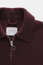 Nahaufnahme aus frontaler Perspektive der 04651/ A trip in a bag Wolljacke 'Boiled Blouson' bordeaux aus Bouclé-Strick, gewalkter reiner Schurwolle, Slim Fit mit Metall-Reißverschluss, Umlegekragen, Raw-Edge-Finish, schräge Leistentaschen, Druckknopf-Ärme