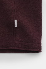 Detailaufnahme von bordeauxfarbener 04651/ A trip in a bag Wolljacke 'Boiled Blouson' aus Bouclé-Strick, gewalkter Qualität mit Raw-Edge-Finish, Weblabel und weichem Griff.