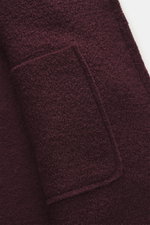 Nahaufnahme von der Tasche der 04651/ A trip in a bag Wolljacke 'Boiled Blouson' bordeaux, Bouclé-Strick, reine Schurwolle, gewalkte Qualität, Raw-Edge-Finish, Slim Fit.
