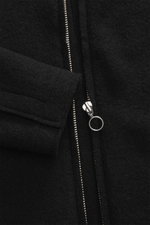 Nahaufnahme der schwarzen 04651/ A trip in a bag Wolljacke 'Boiled Blouson' mit Metall-Reißverschluss, Raw-Edge-Finish, Umlegekragen, Slim Fit, Bouclé-Strick aus reiner Schurwolle, gewalkte Qualität, weicher Griff, schräge Leistentaschen, Ärmelabschlüsse 